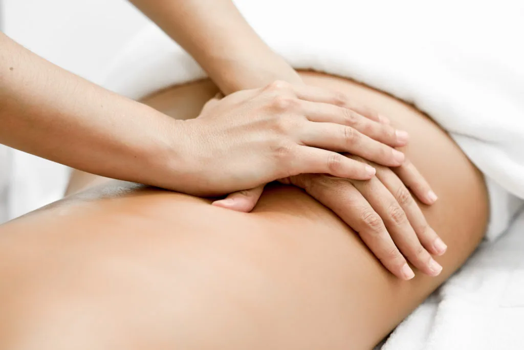 Therapist's hands performing a massage on a patient's leg and thigh